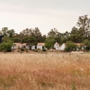 Wide view of Casas na Ferraria buildings set within open fields and trees.