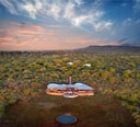 Aerial view of Morukuru Farm House set within dense African bushveld at sunset.