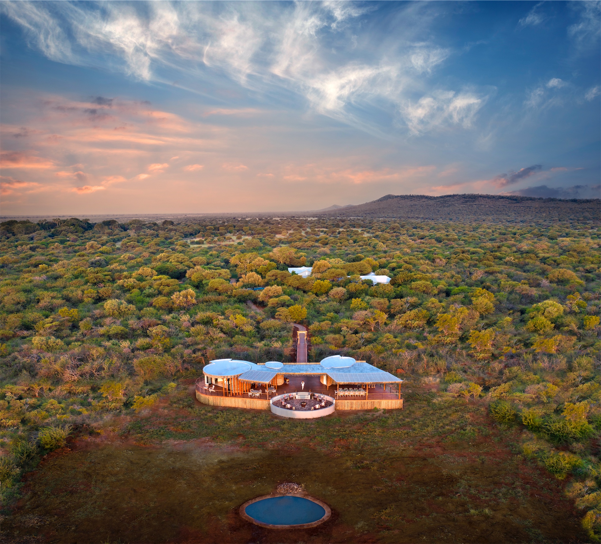 Aerial view of Morukuru Farm House set within dense African bushveld at sunset.