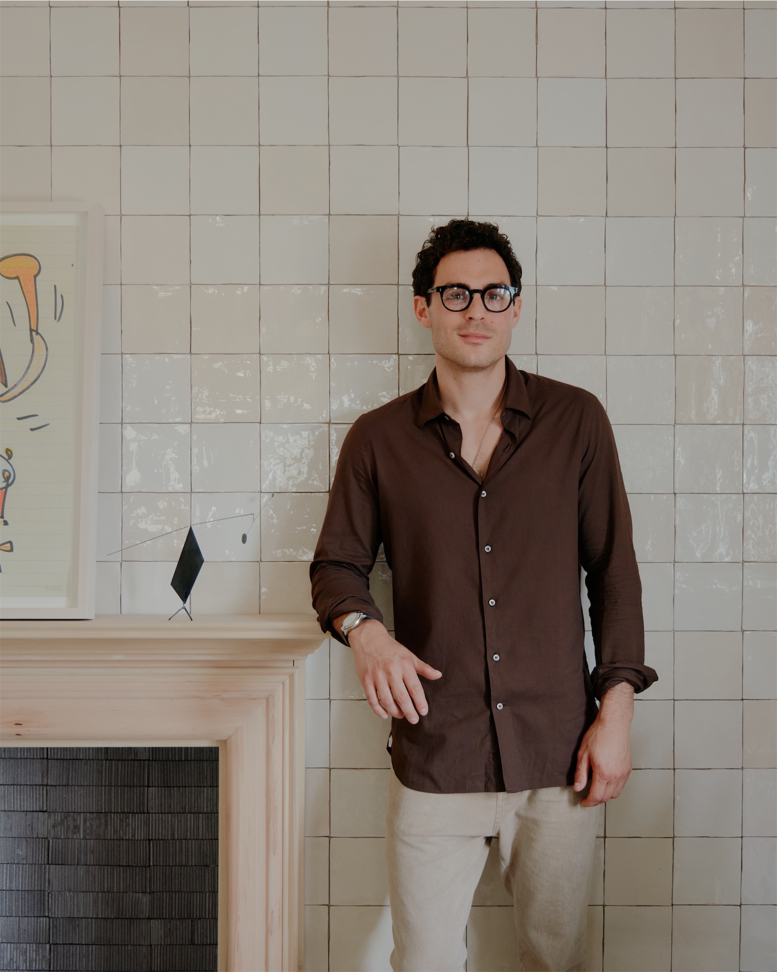 George DiStefano, Owner and Creative Director of The James Bradley, standing in front of a tiled fireplace wall.