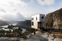 Vipp Bolder cabin overlooking fjord and mountain landscape.