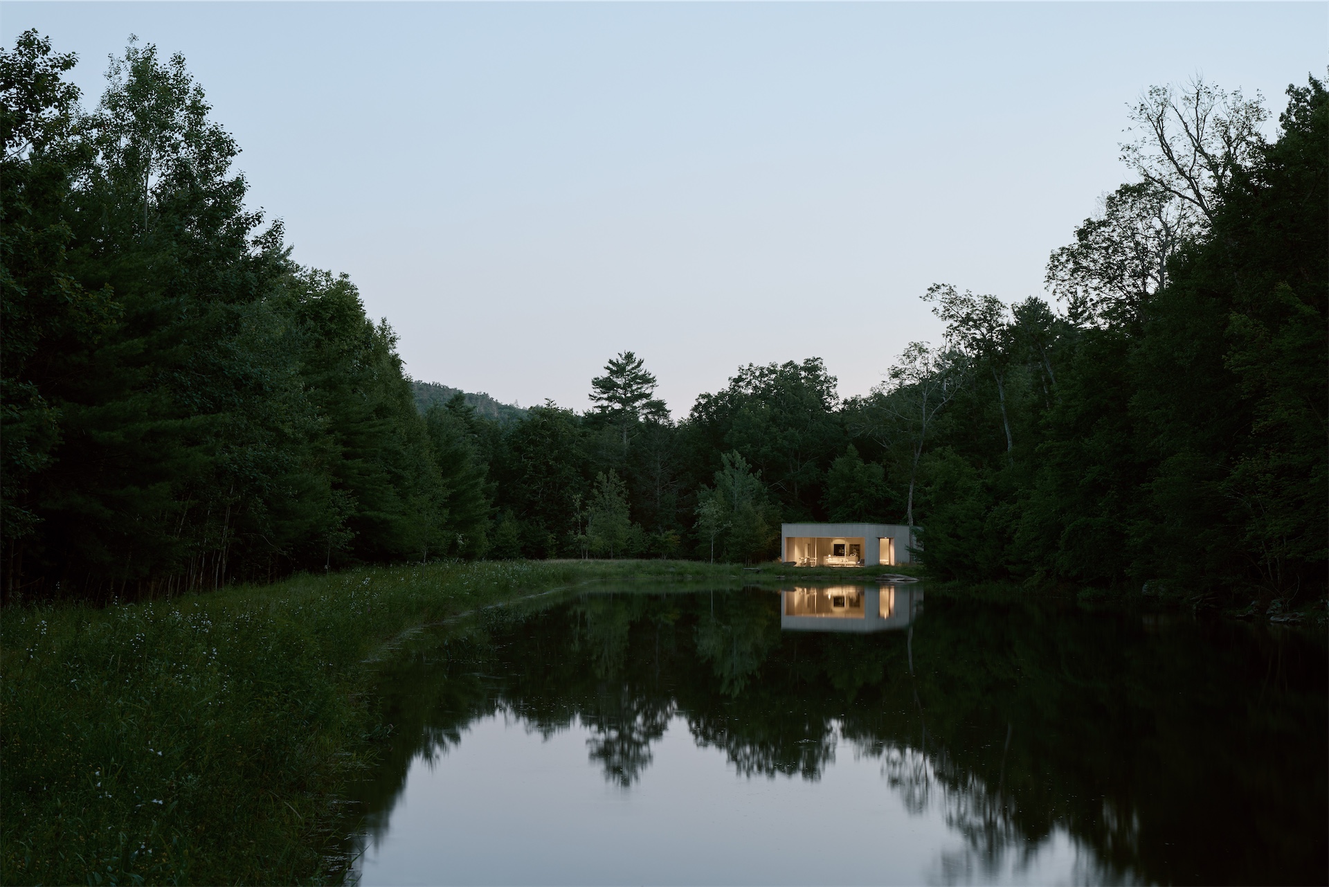 Vipp Pavilion reflected in a quiet pond surrounded by forest in Upstate New York