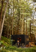 https://cms.here-away.com/wp-content/uploads/2026/04/postcard-cabins-forest-exterior-woman-arrival.jpg